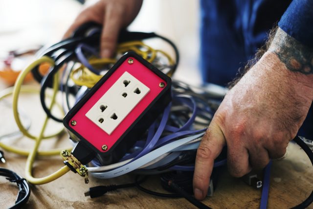 Imagem de maos masculinas mexendo em fios elétricos