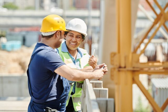 Homem e mulher com equipamentos de construção civil conversando em uma obra